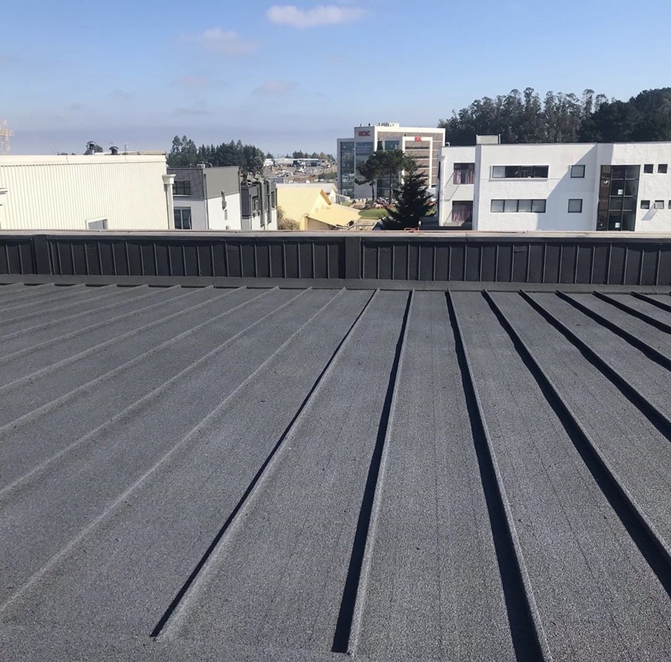 Completed grey spray cork roof coating over a ribbed metal deck